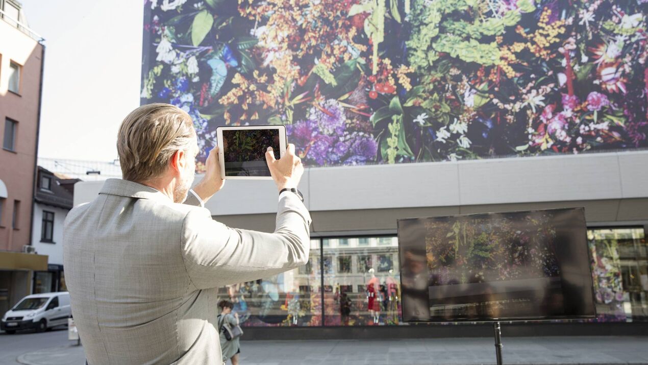 Person mit AR Anwendung auf einem Tablet vor der ITFS Wall of animation