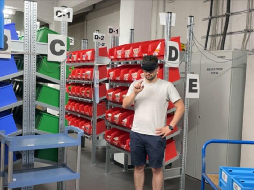 Kommissionierer mit VR Brille vor Lagerregalen