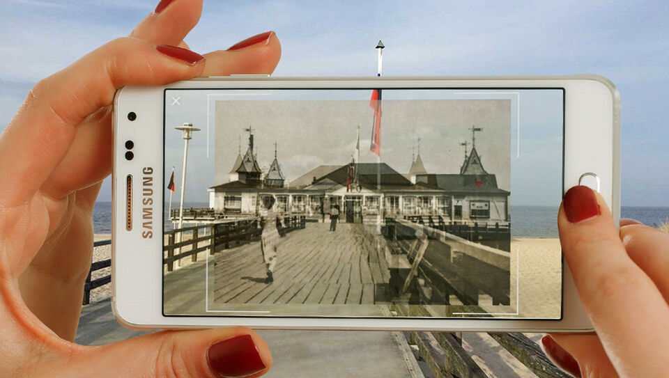 iPhone vor alter Seebrücke mit Bild von damals in der App